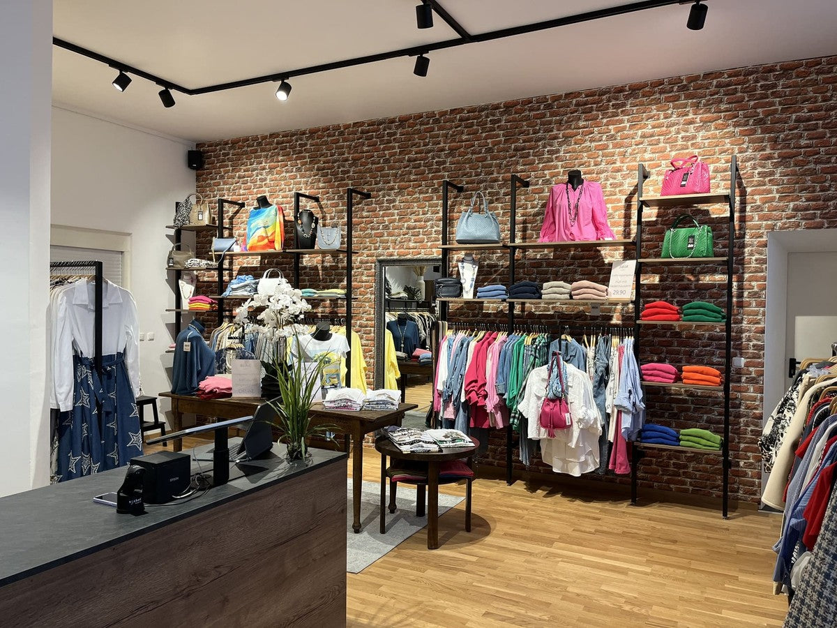 Einblick in die Bella Vita Boutique in Miesbach: liebevoll dekorierter Verkaufsraum mit italienischer Damenmode, farbenfrohen Kleidungsstücken und stilvollen Accessoires.