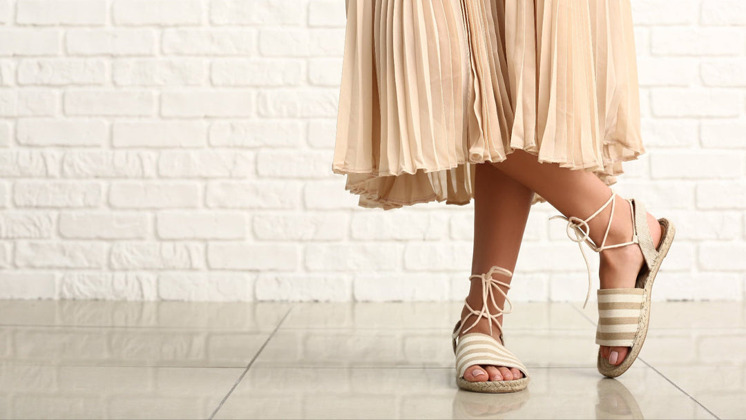 Elegante Damen-Sandalen von NeroGiardini mit Schnürung und Bastsohle – stilvoll kombiniert mit einem plissierten Rock für einen sommerlich-leichten Look.