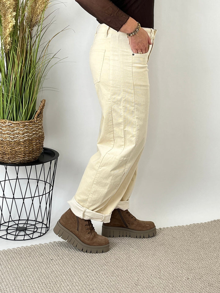 Dreiviertel-Seitenansicht der beigen Cordhose mit umgeschlagenem Bein und seitlicher Ziernaht