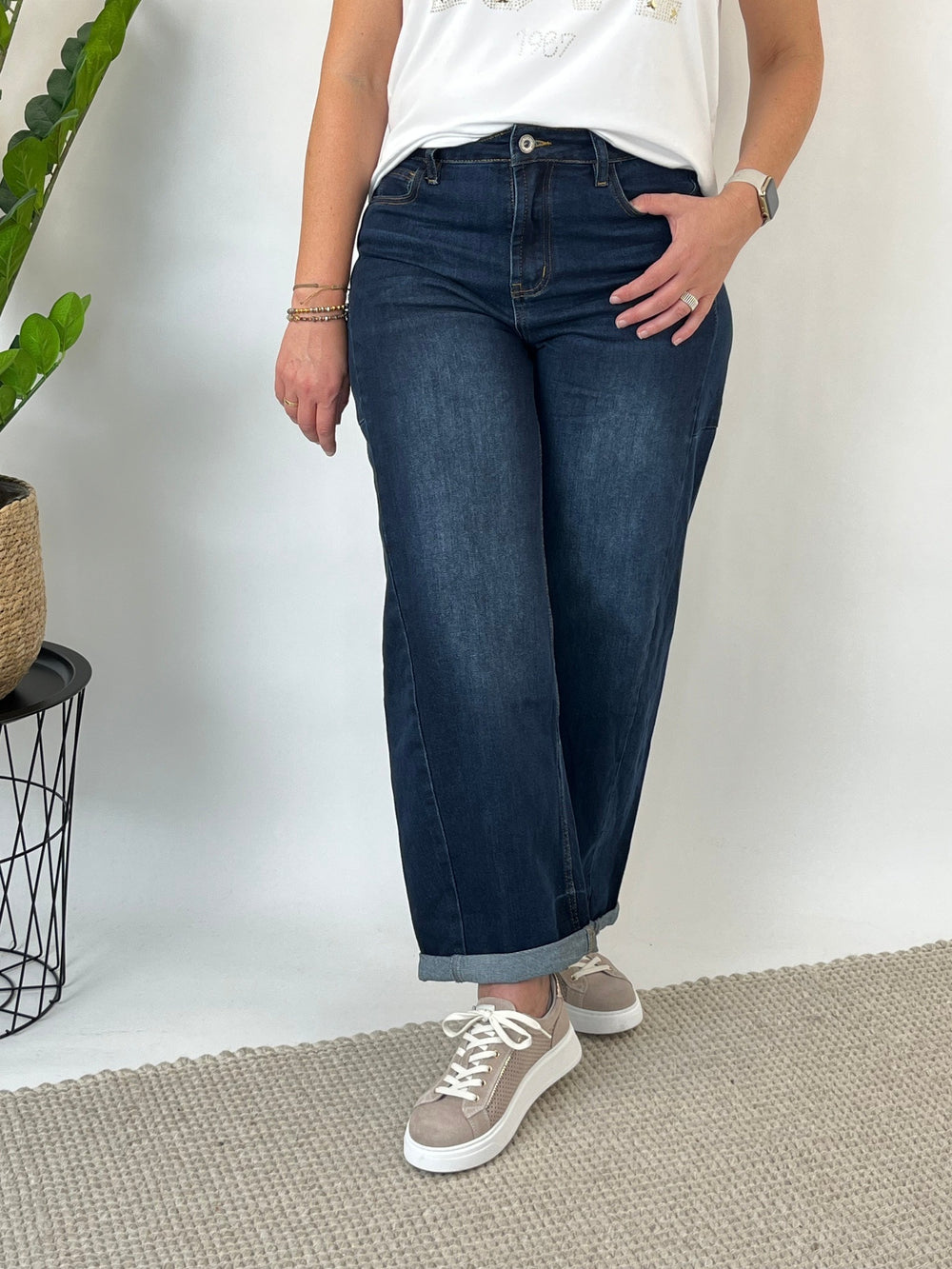 Frontalansicht der dunkelblauen Barrel Jeans mit silbernem Knopf und orangefarbenen Nähten