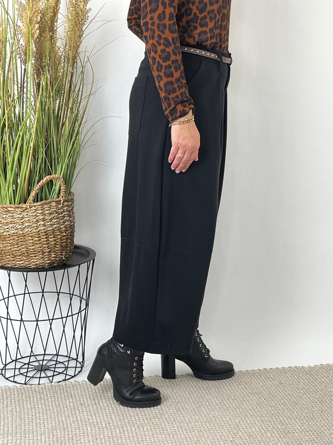 Seitenansicht der schwarzen Hose: lockere Barrelform und horizontale Naht