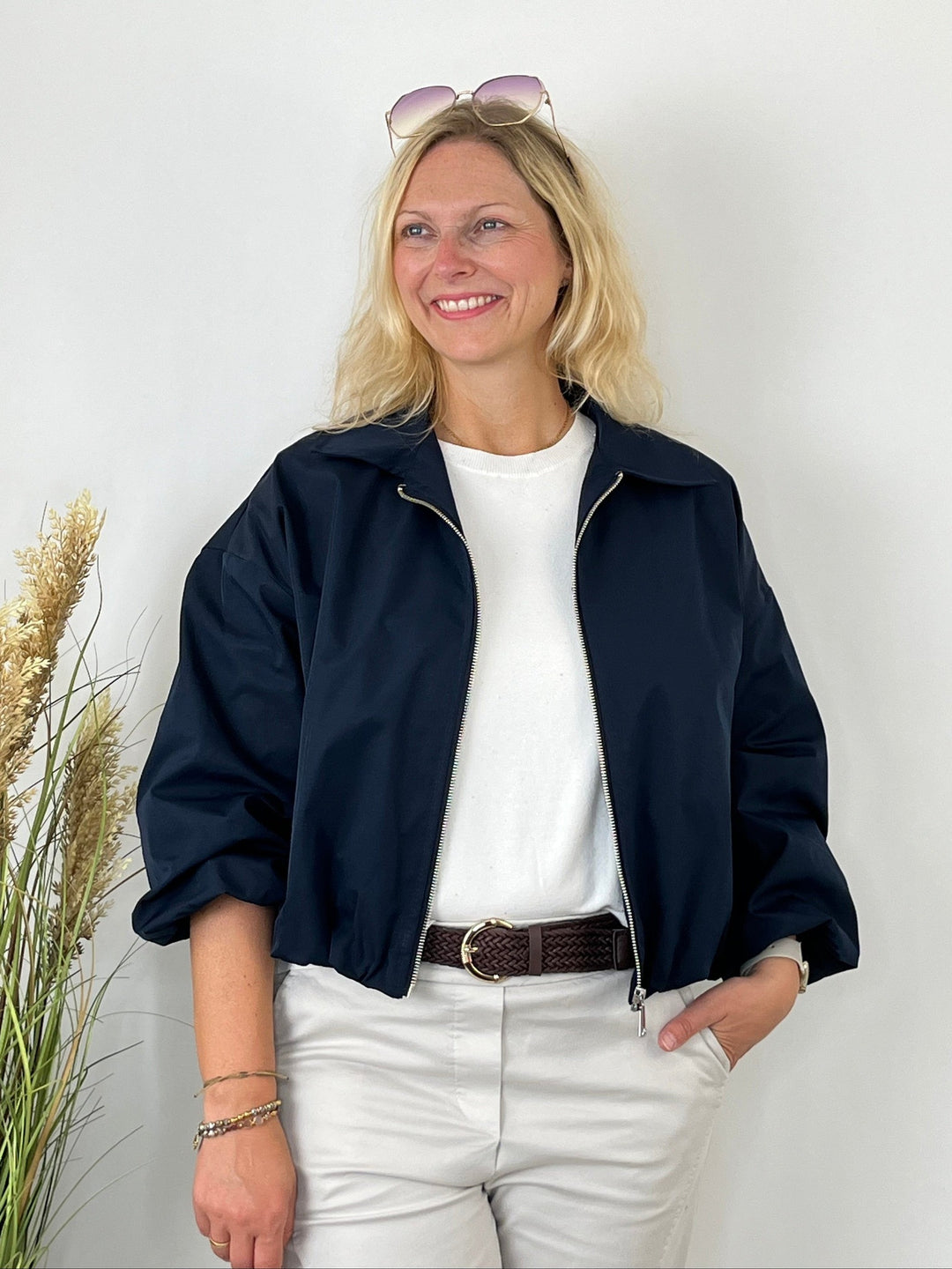 Offen getragene marine Blousonjacke über weißem Oberteil
