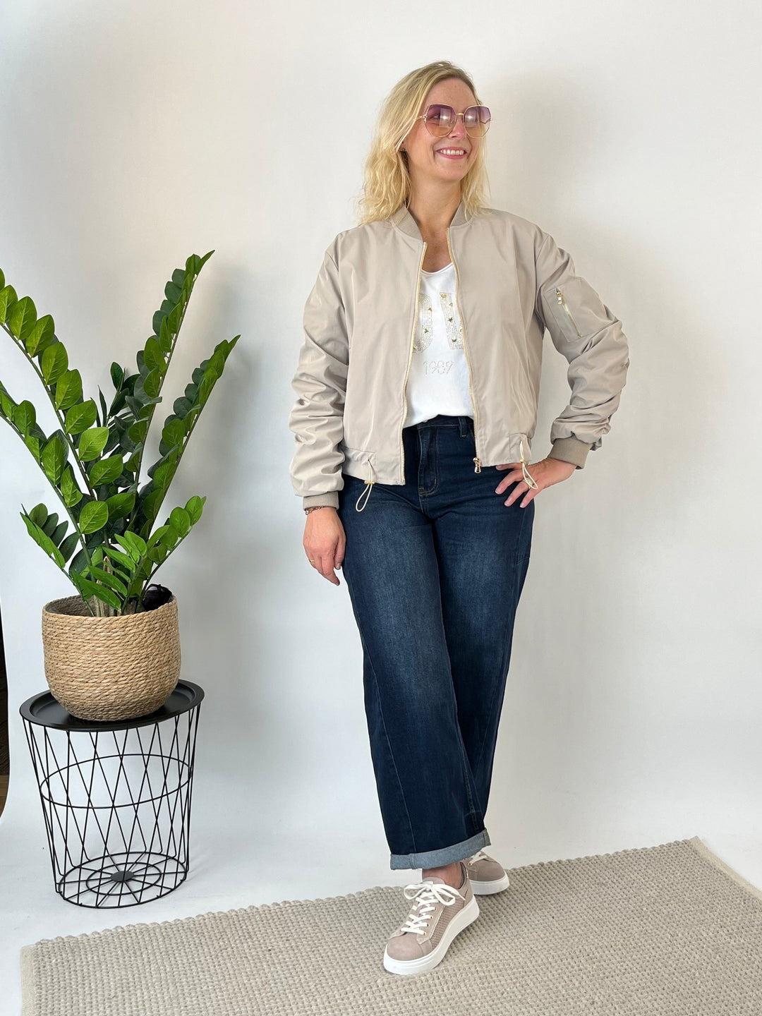 Ganzkörperansicht beige Bomberjacke mit Sneakers und Jeans