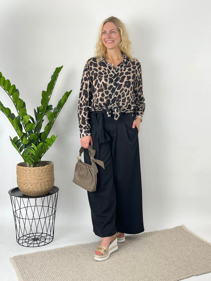 Schwarz-beige Wildtier-Bluse im Knoten-Stil mit schwarzen Hosen und Handtasche
