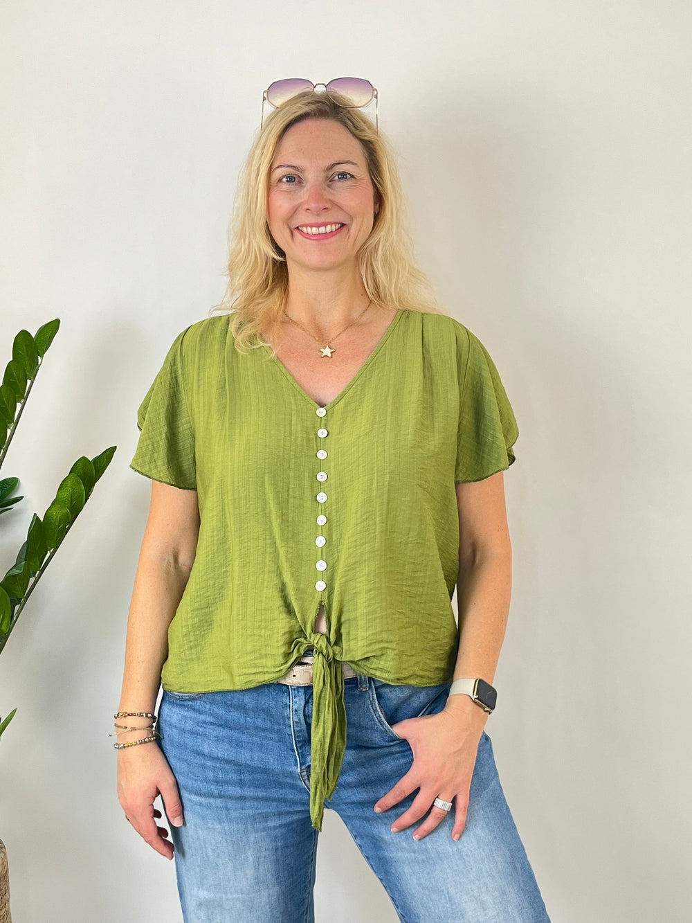 Grüne Damenbluse mit Volantärmeln, V-Ausschnitt und Knotendetail am Saum