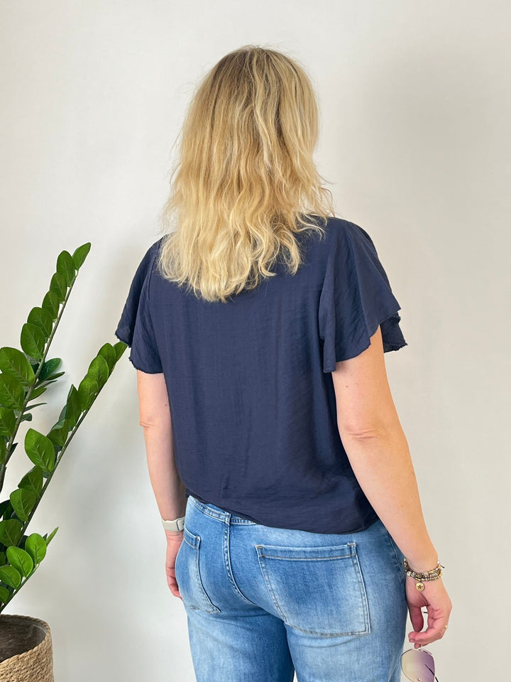 Rückansicht marineblaue Bluse mit locker fallendem Saum und Volantärmeln