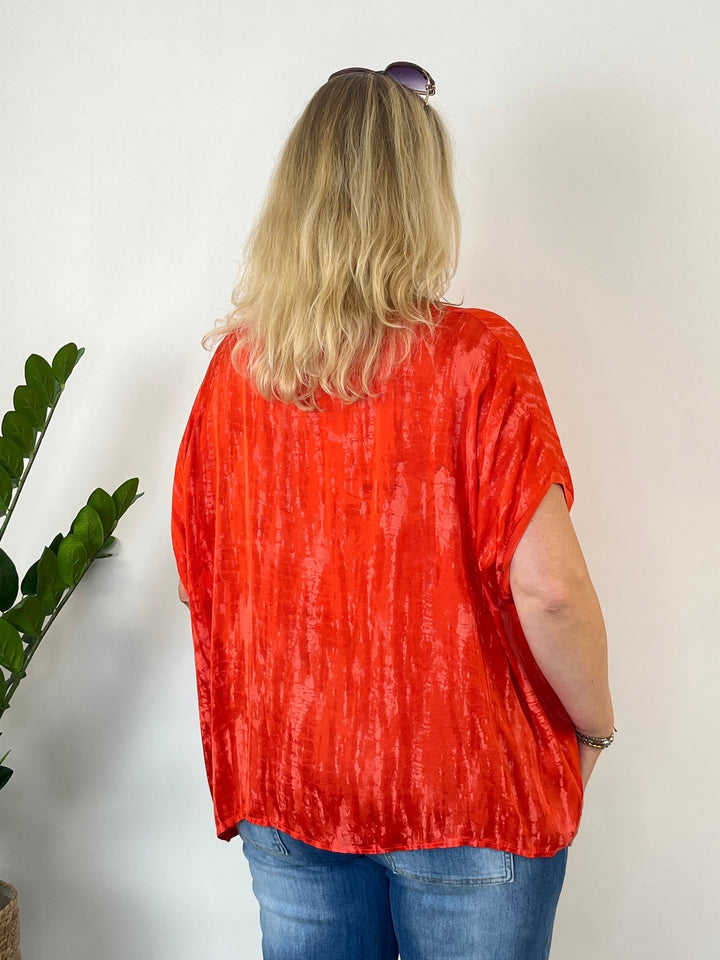 Rückansicht orange Blusenshirt mit grafischem Muster und gewelltem Saum