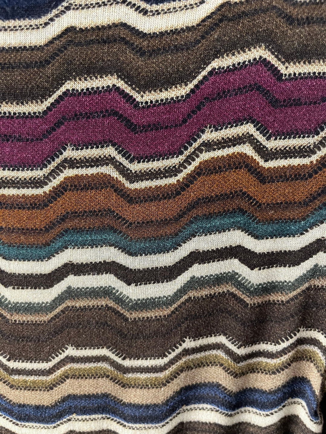 Nahaufnahme feiner Stricktextur und buntes Wellenmuster des Shirts