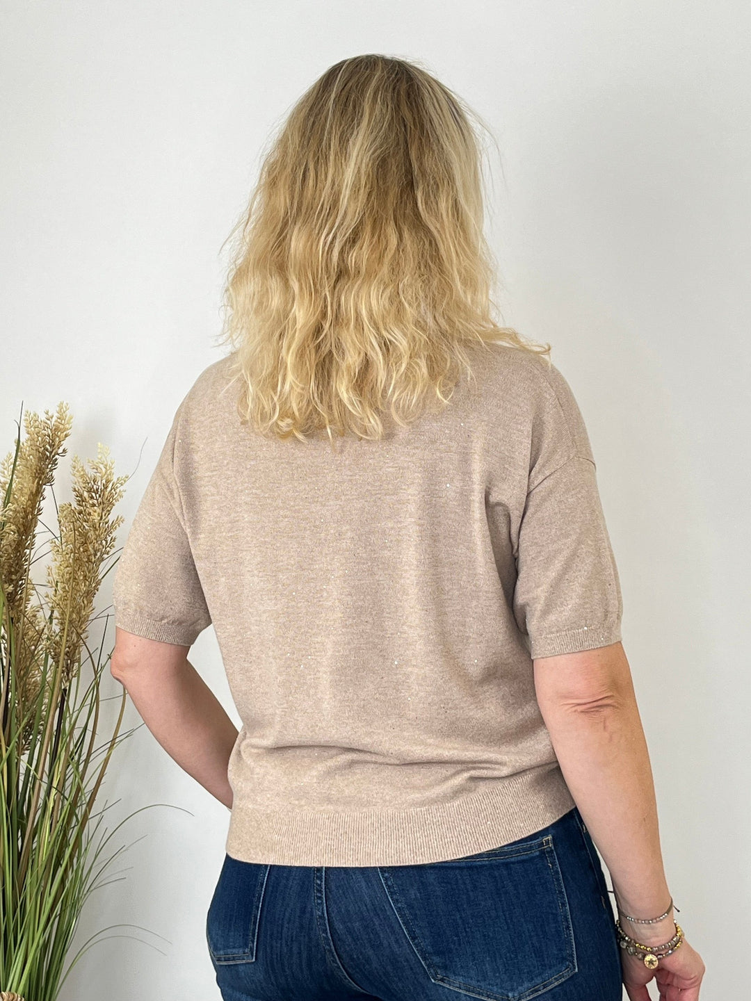 Rückansicht des beige Feinstrickpullovers mit Jeans