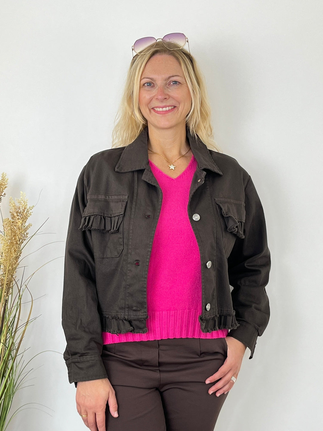 Kurze braune Jeansjacke mit Rüschen über pinkem Pullover