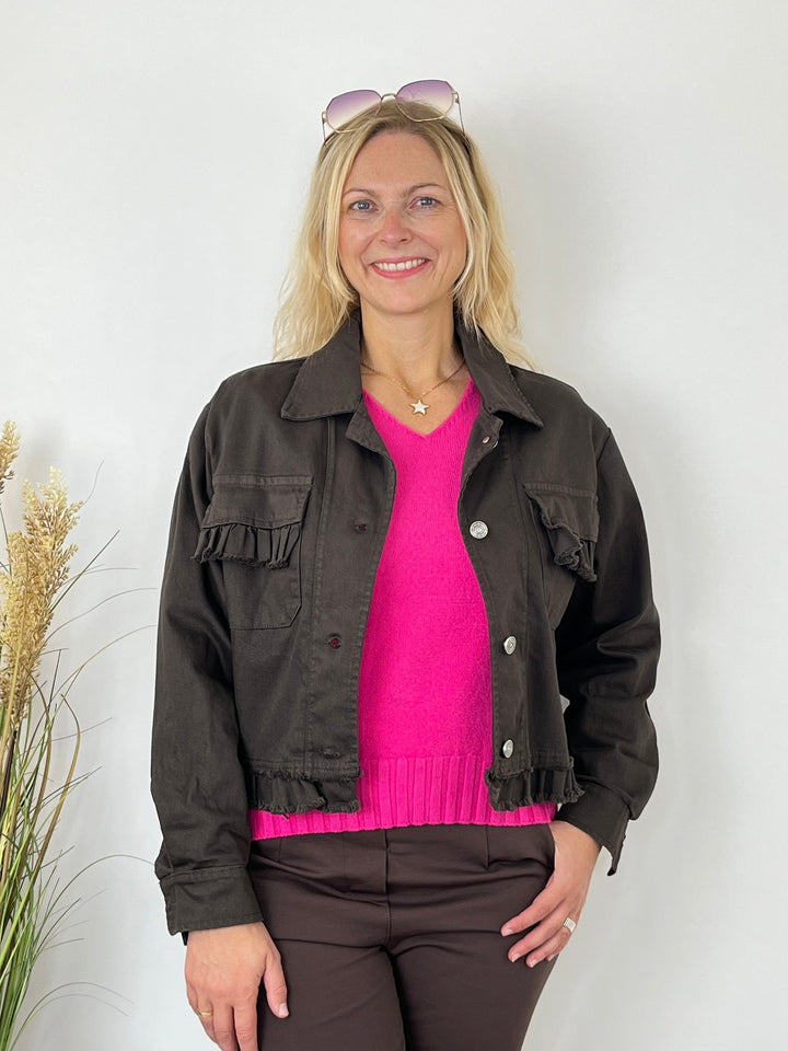 Kurze braune Jeansjacke mit Rüschen über pinkem Pullover