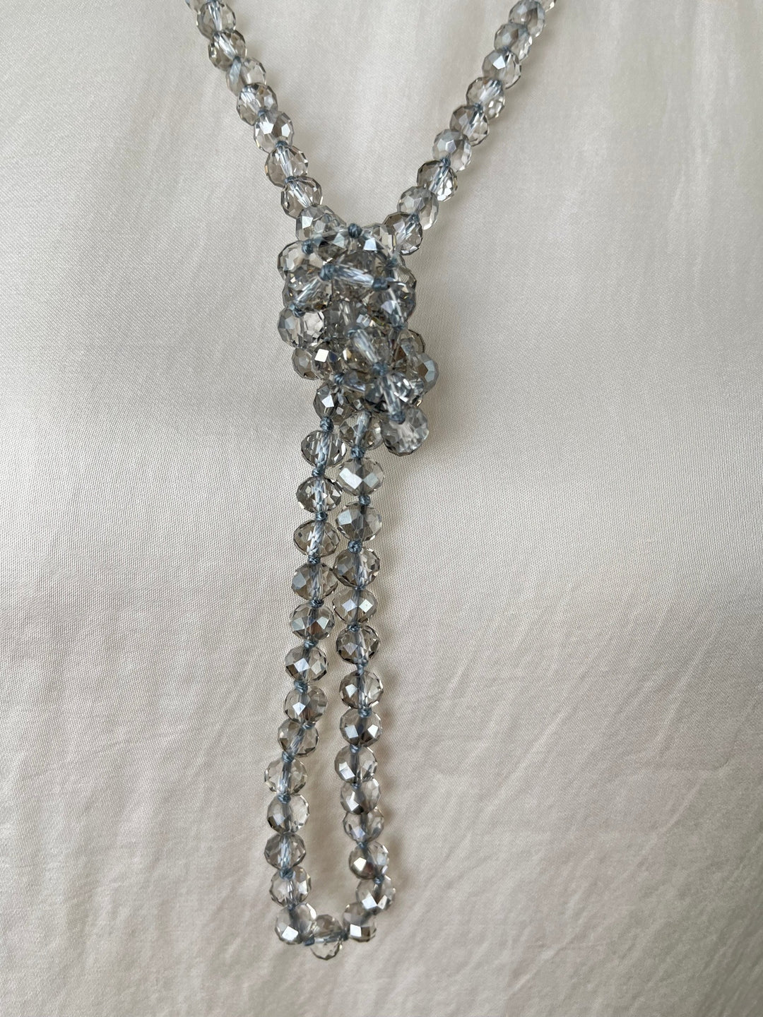 Nahaufnahme gebundener grauer Glaskette als Y-Kette mit hellblauer Schnur