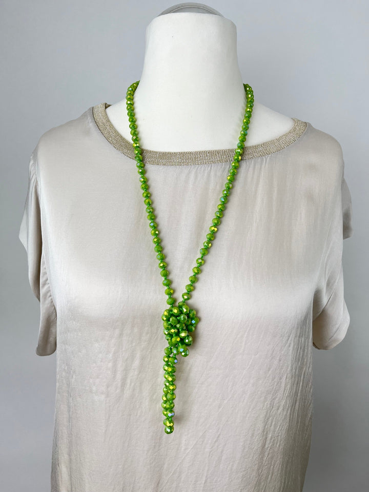 Grüne Halskette mit facettierten Glassteinen und zentralem Perlenanhänger am Mannequin