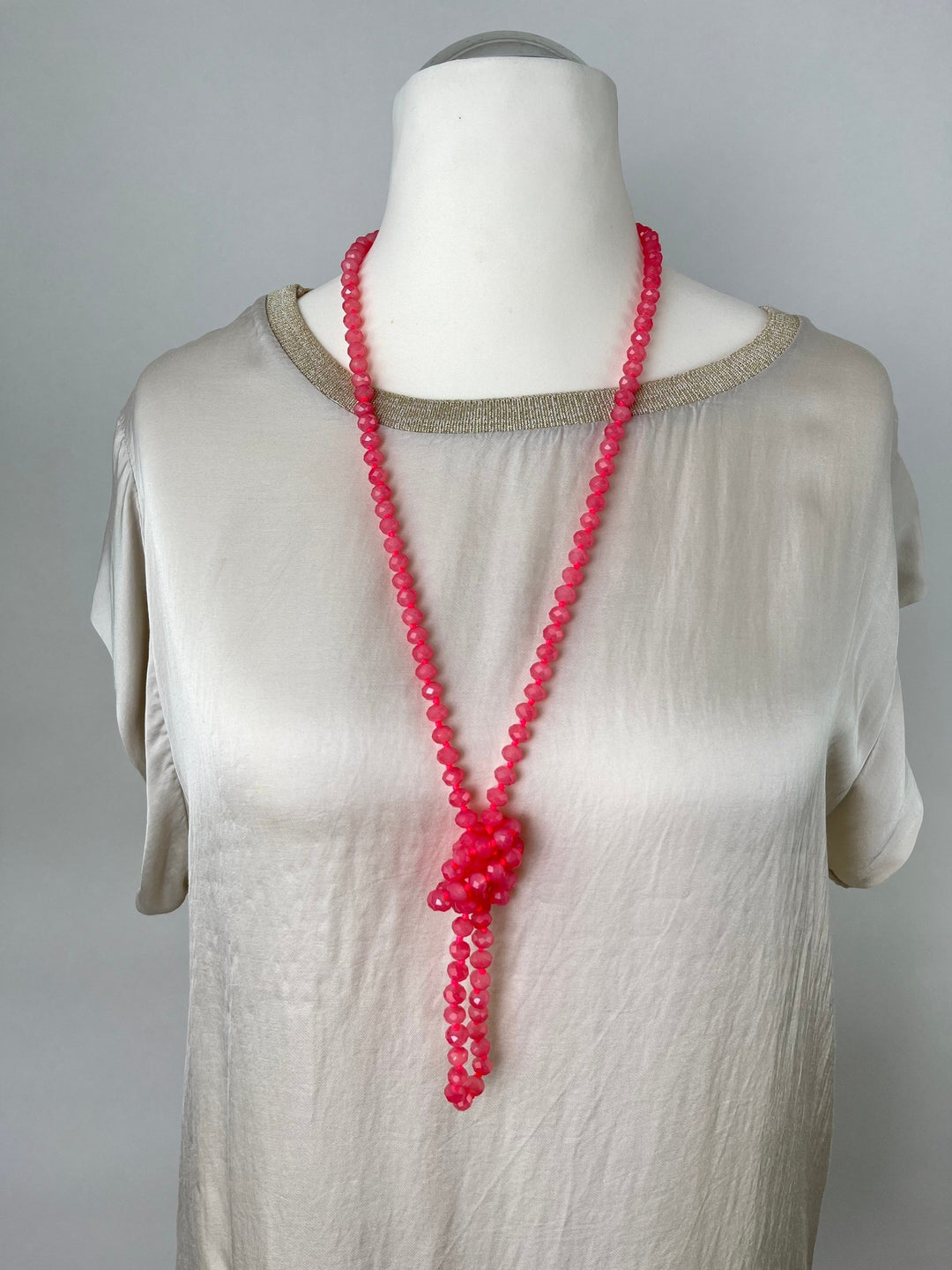 Korallenfarbene Glassteinkette mit Knotendetail an Mannequin