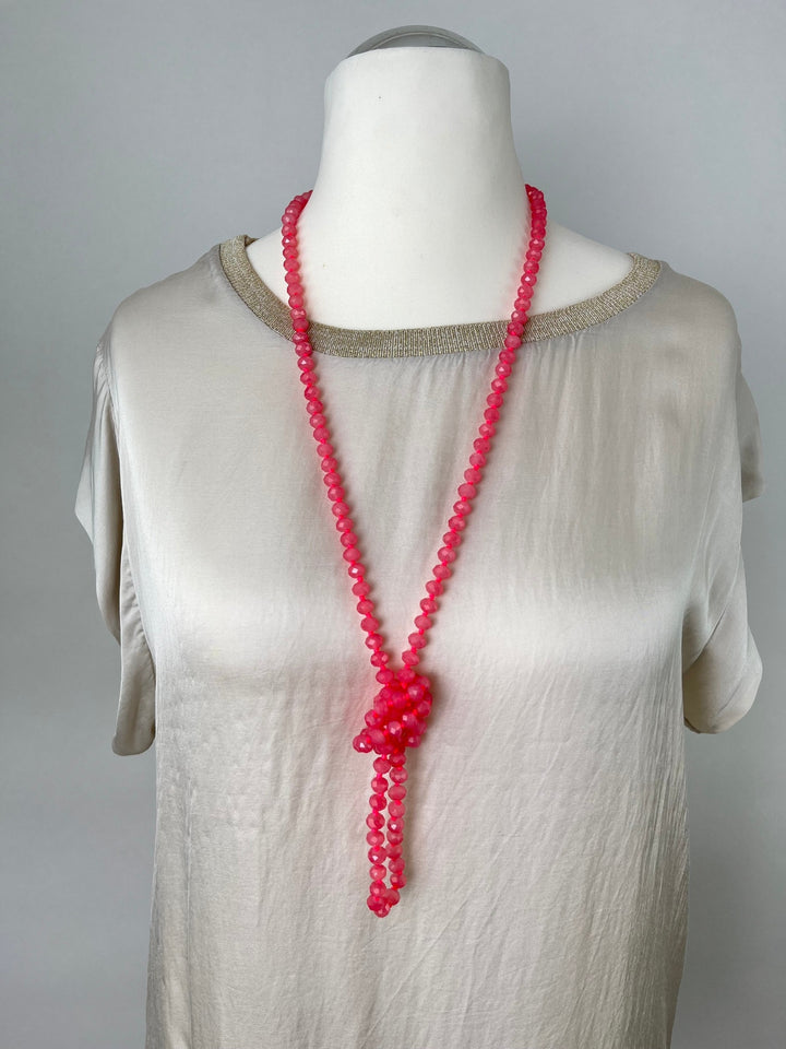 Korallenfarbene Glassteinkette mit Knotendetail an Mannequin