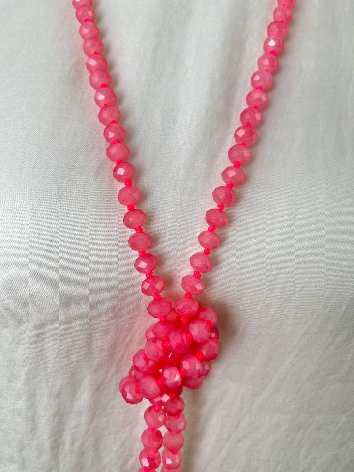 Nahaufnahme facettierter rosa Glassteine und V-förmiger Kette