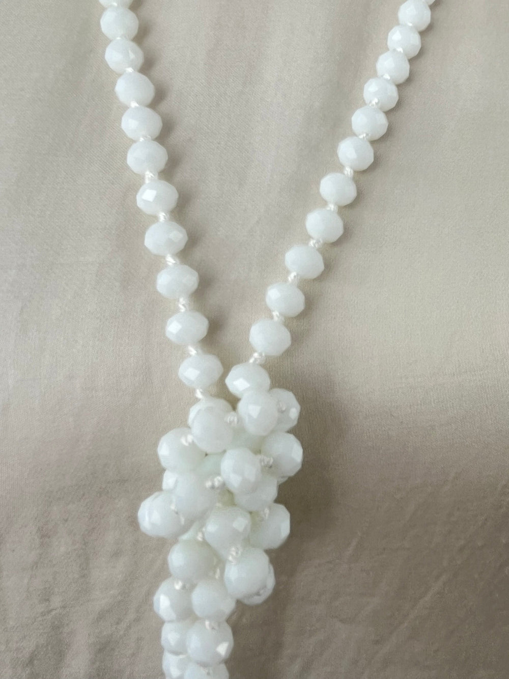 Detailansicht weißer Glasstein-Kette mit blütenförmigem Knoten und Metallperlen