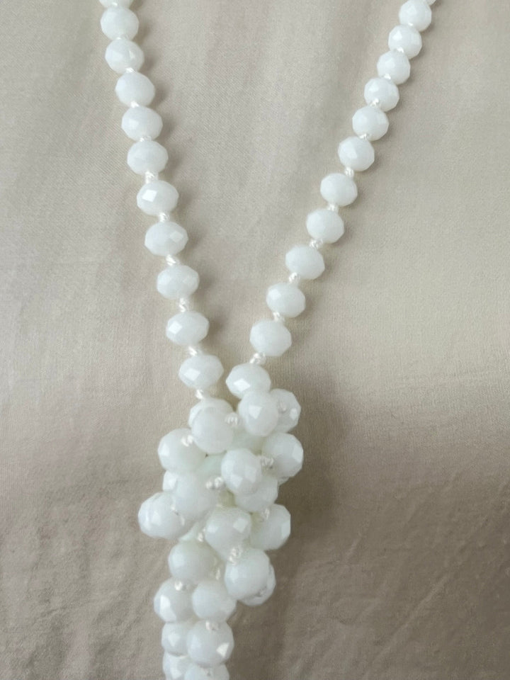Detailansicht weißer Glasstein-Kette mit blütenförmigem Knoten und Metallperlen