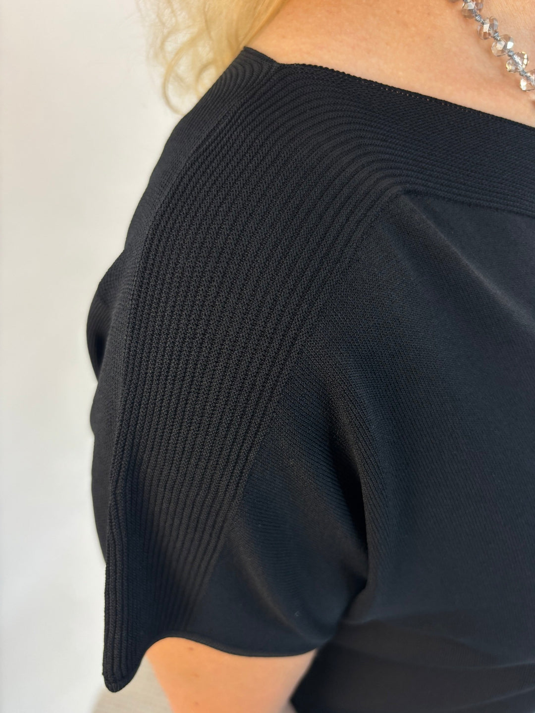 Schwarzer Kurzarm-Pullover mit U-Boot-Ausschnitt, Detail der feinen Rippstruktur an der Schulter