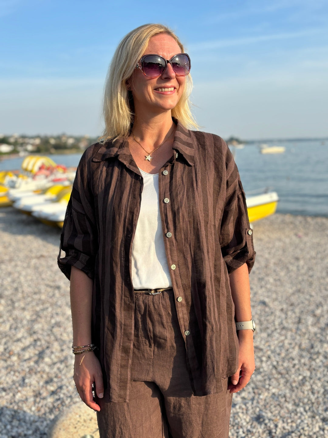 Braune Leinenbluse mit Streifen und hochgekrempelten Ärmeln am Strand