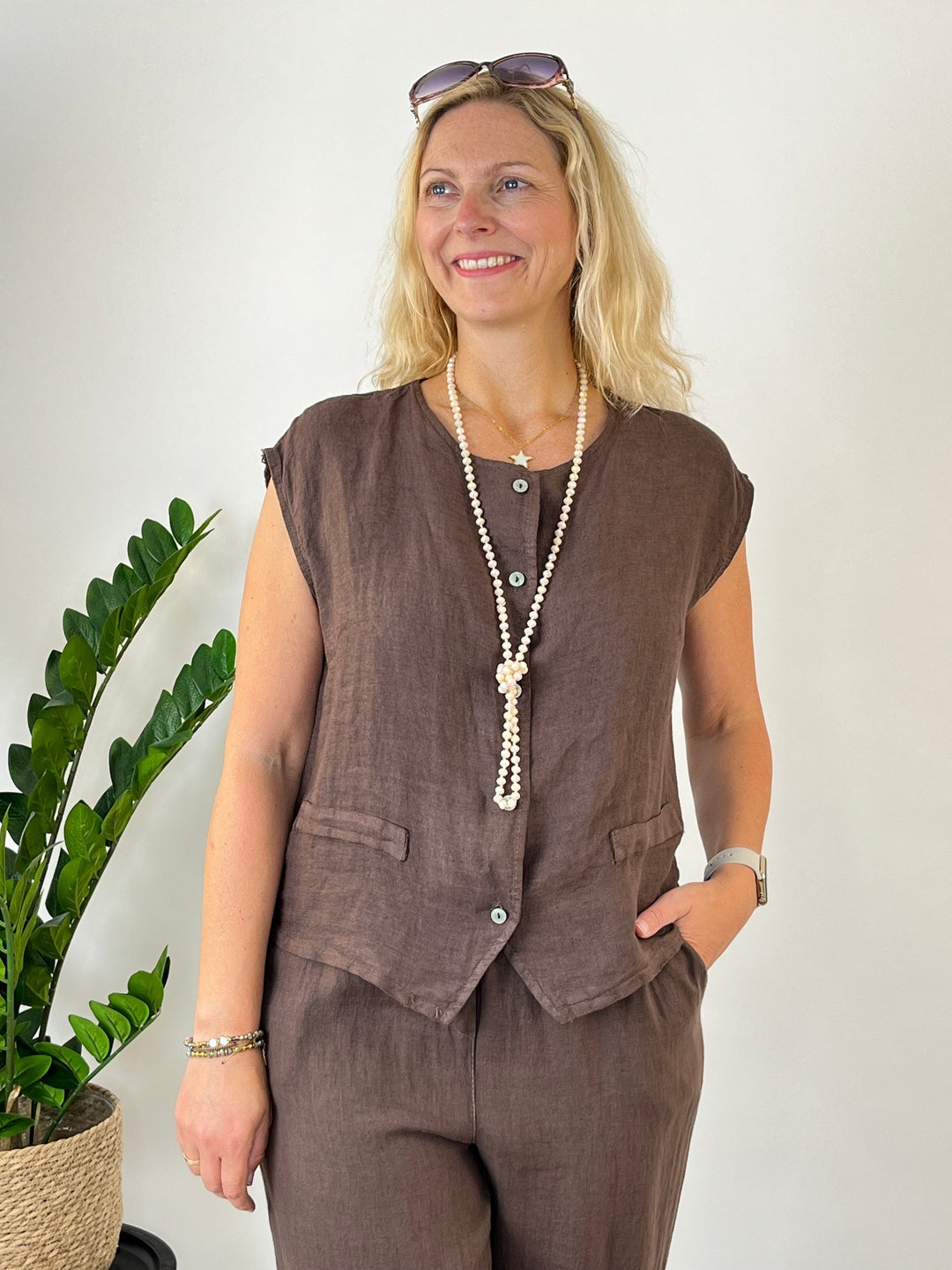 Braune Leinenweste Damen Halbfigur mit Perlenkette und Sonnenbrille