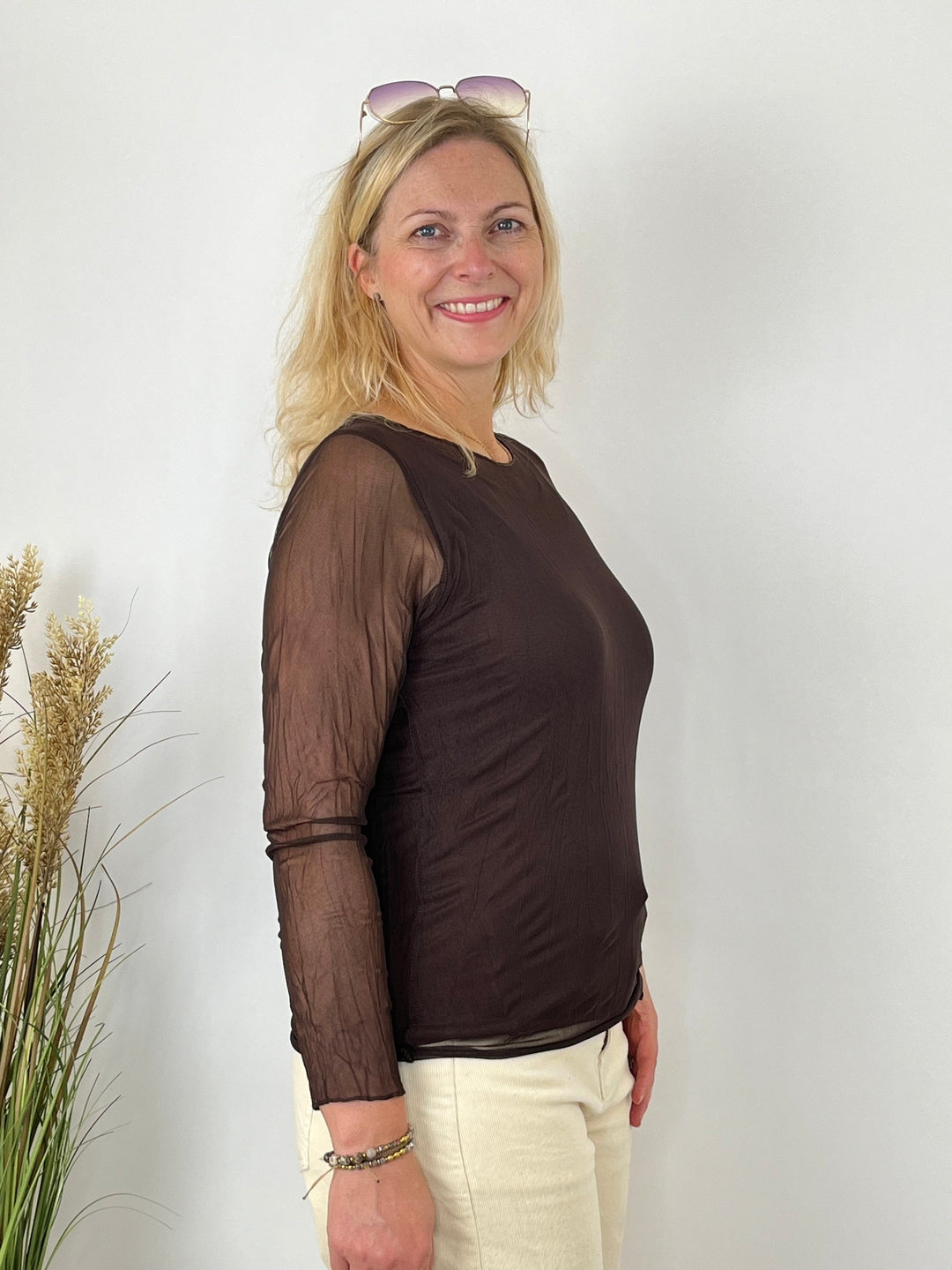 Seitenansicht des braunen Mesh-Shirts mit rundem Ausschnitt und durchsichtigen Ärmeln
