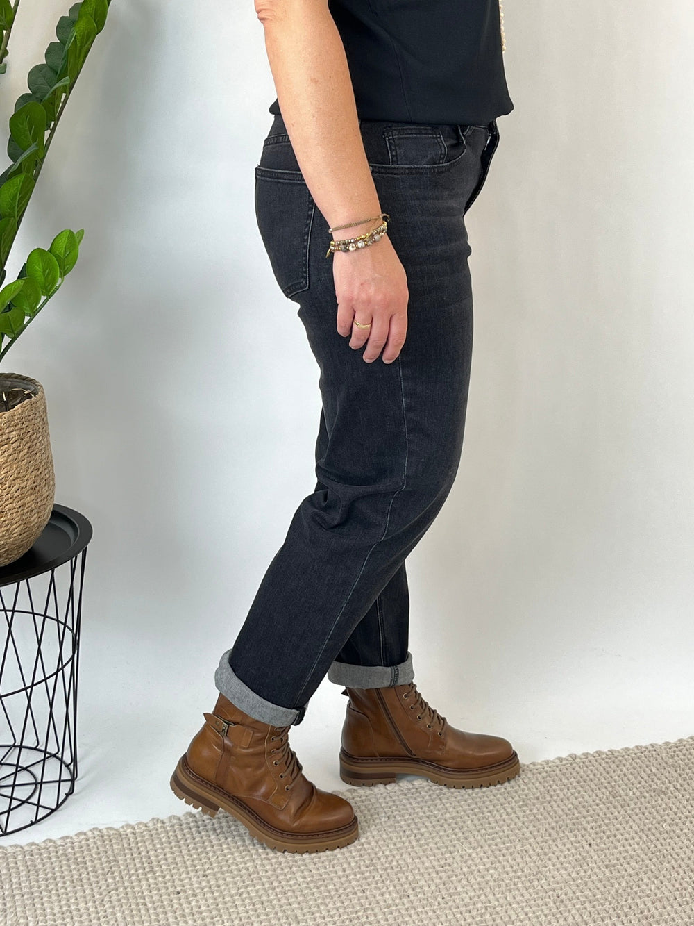 Seitenansicht der schwarzen Relaxed Jeans mit braunen Lederstiefeln und aufgerolltem Saum