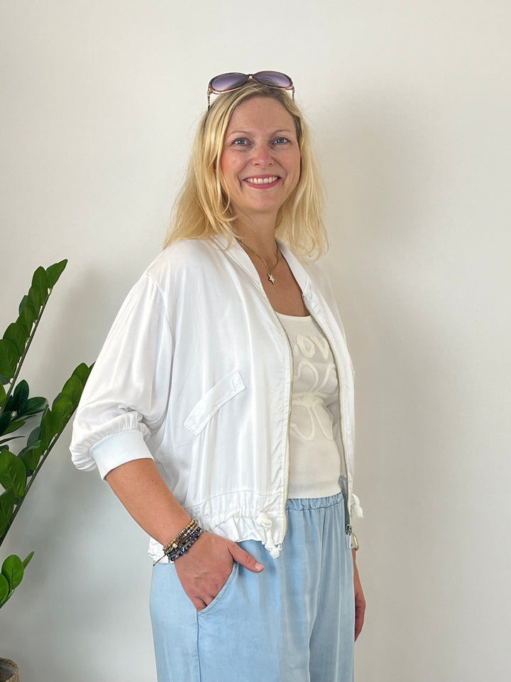 Seitenansicht weiße Satinjacke mit geöffnetem Gold-Reißverschluss und Taschen