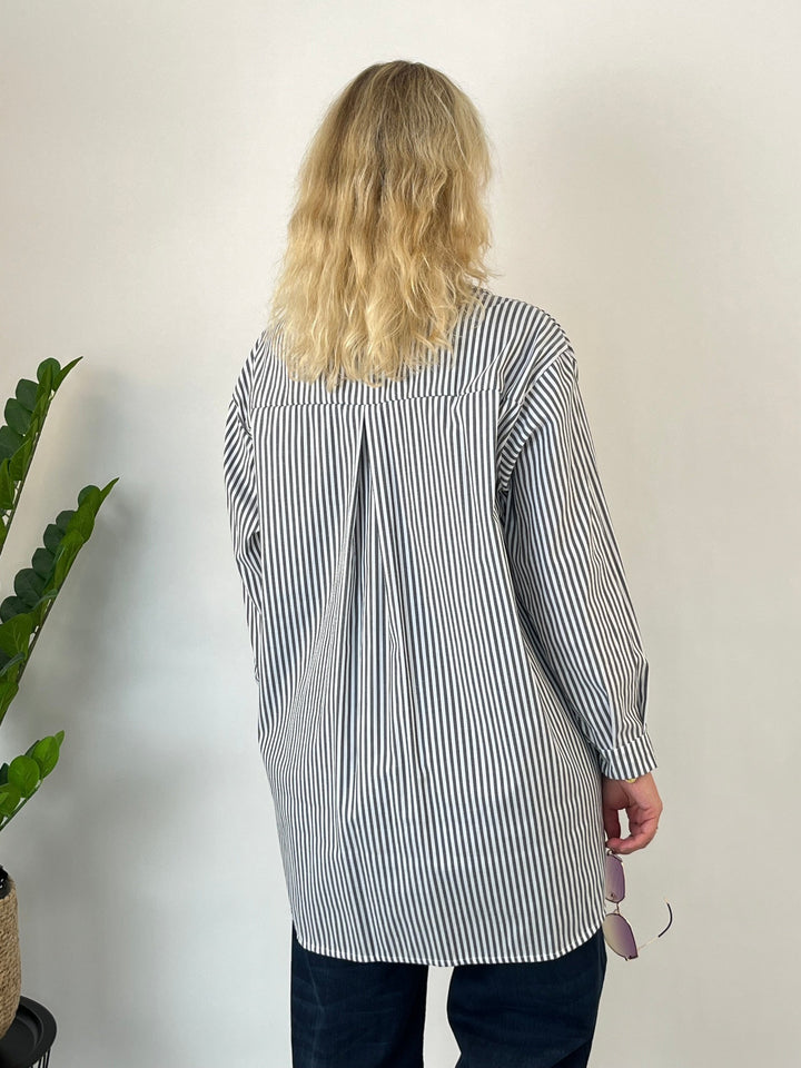 Rückansicht grau-weiße Longbluse mit zentraler Fasson und abgerundetem Saum