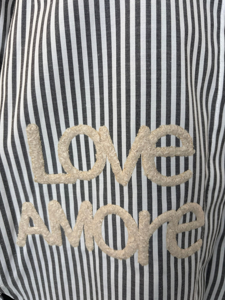 Detailaufnahme voluminöser Love AMORE Stickerei auf gestreifter Stoffoberfläche