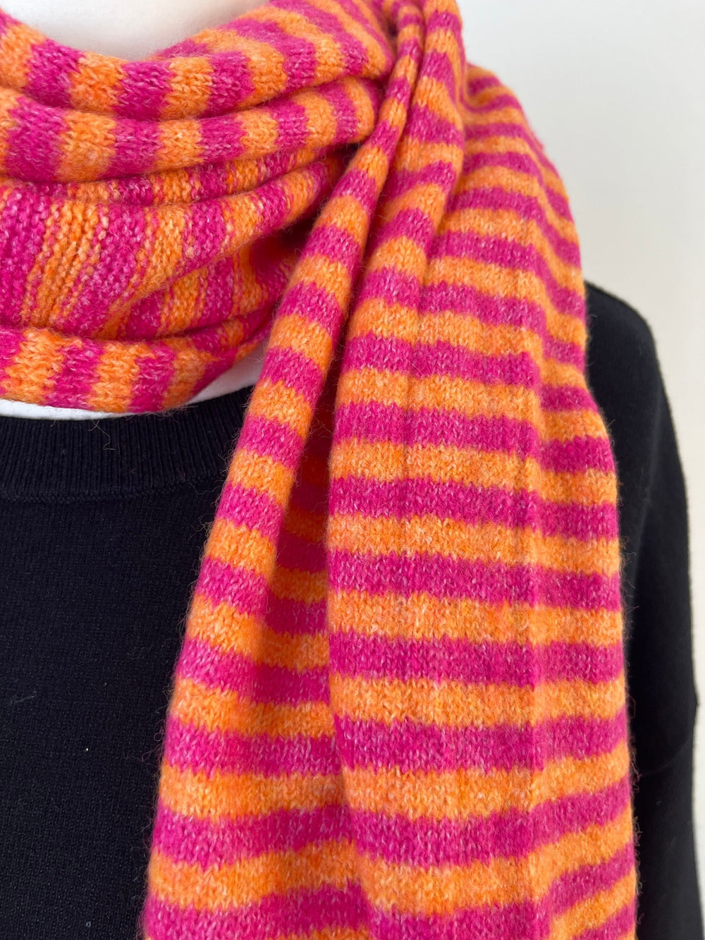 Nahaufnahme: Viskose-Wollmischung Strickschal mit pink-orangen Streifen