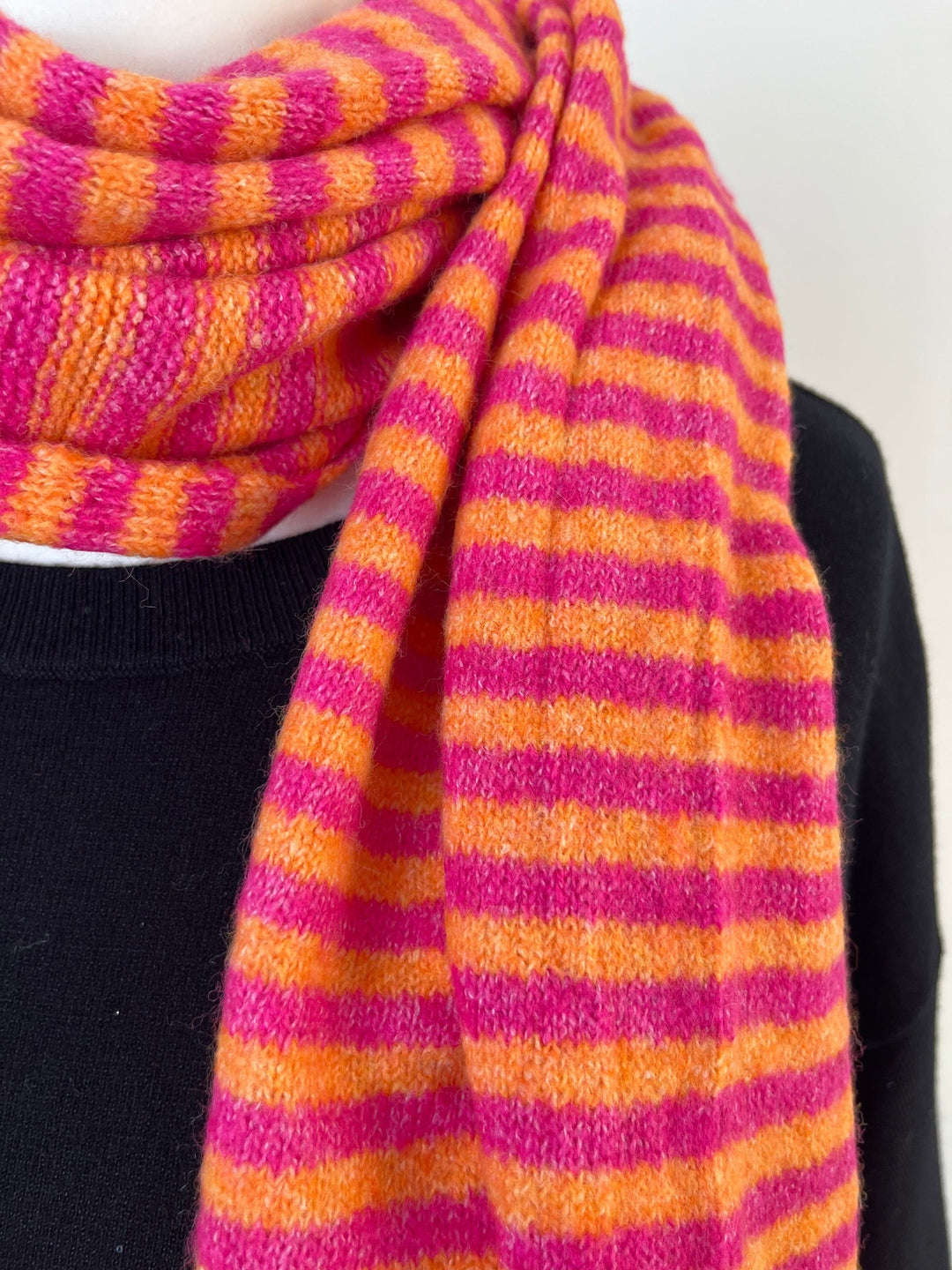 Nahaufnahme: Viskose-Wollmischung Strickschal mit pink-orangen Streifen