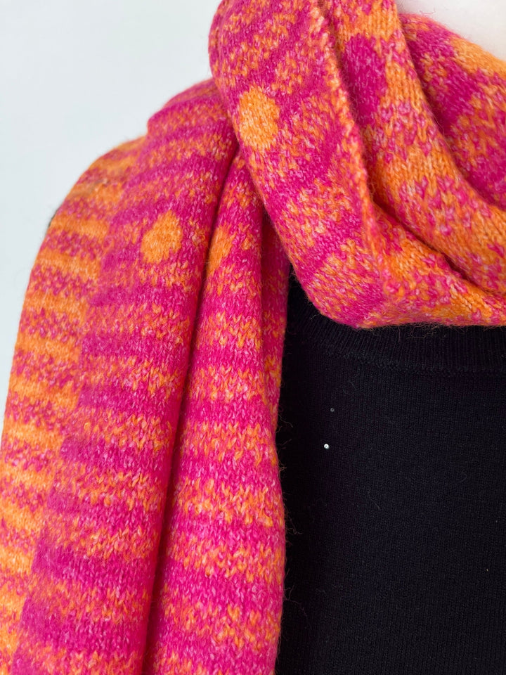 Pink-orangener Strickschal mit Streifen- und Punktmuster, getragen über schwarzem Oberteil
