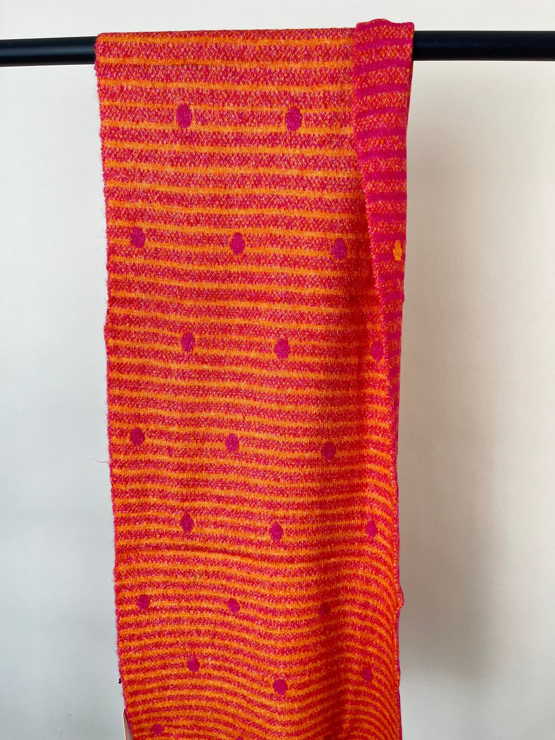 Flach ausgelegter pink-oranger Schal mit Streifen- und Punktdesign