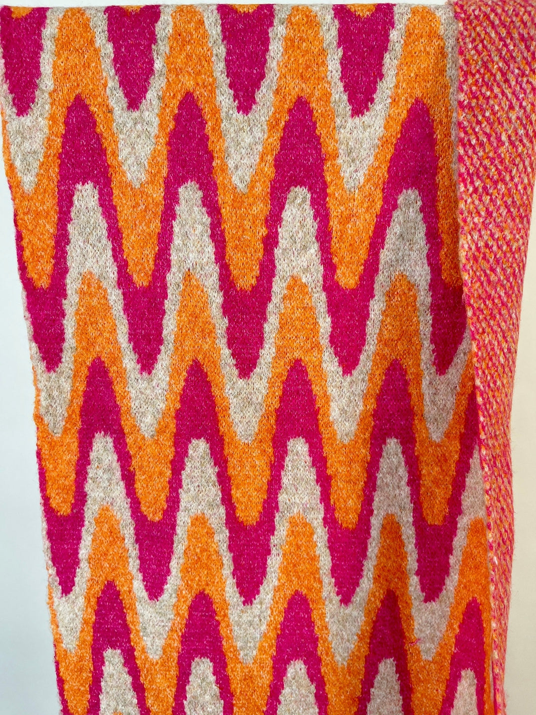 Nahaufnahme der weichen Stricktextur des orangefarbenen Schals