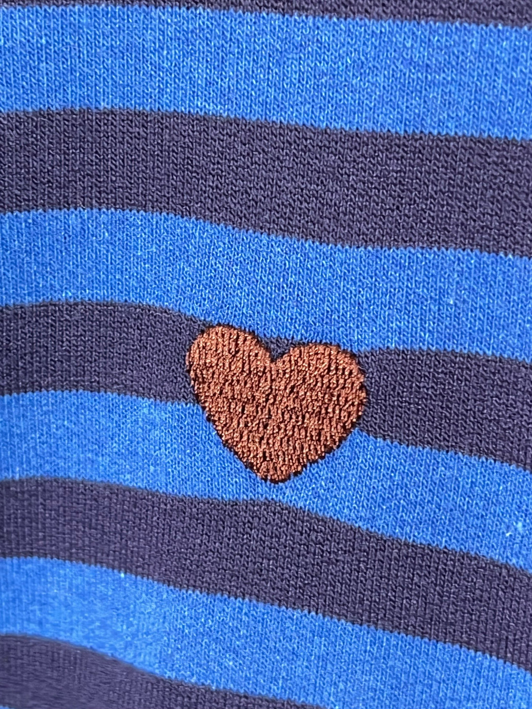 Nahaufnahme blau-mariner Streifen und Herzstickerei am Sweater