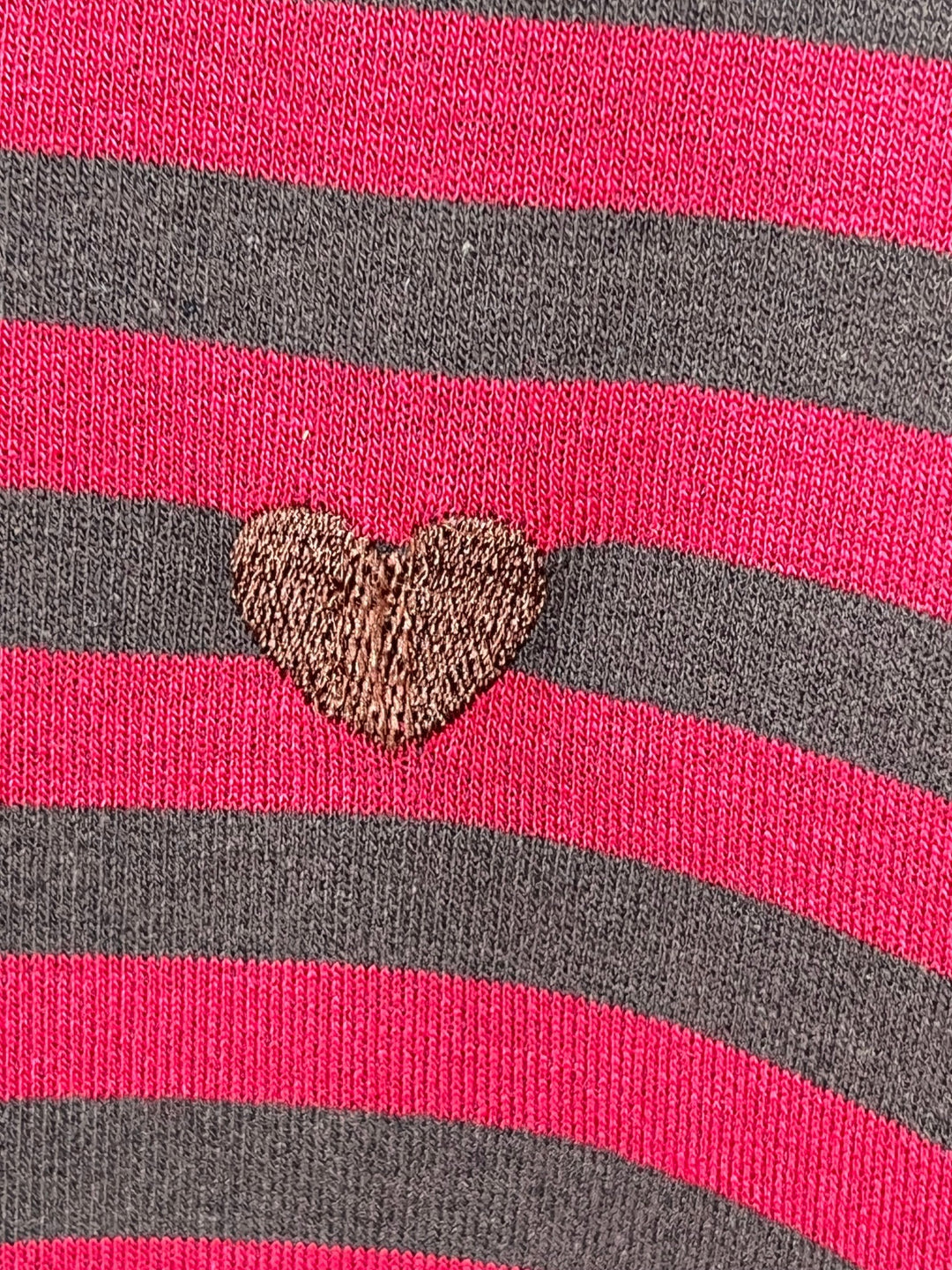 Nahaufnahme der Streifenmusterung und Herzstickerei am Sweater