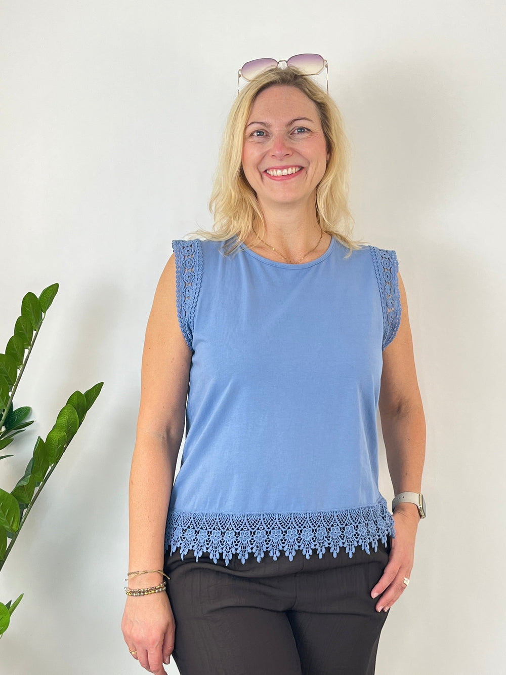 Frau trägt hellblaues ärmelloses Top mit Häkelspitzen-Detail im Sommer-Look