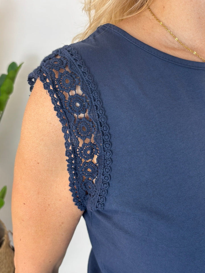 Detailaufnahme der floralen Häkelspitzen-Applikation an der Schulter eines marineblauen Tops