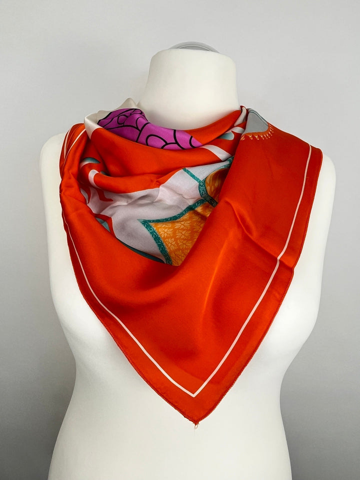 Oranges Seidentuch mit Blumenmotiv und Türkisakzent um Hals