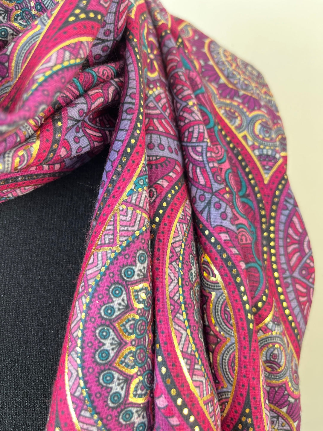 Detailansicht gefalteter Viskoseschal mit lila Ornamenten und Golddetails