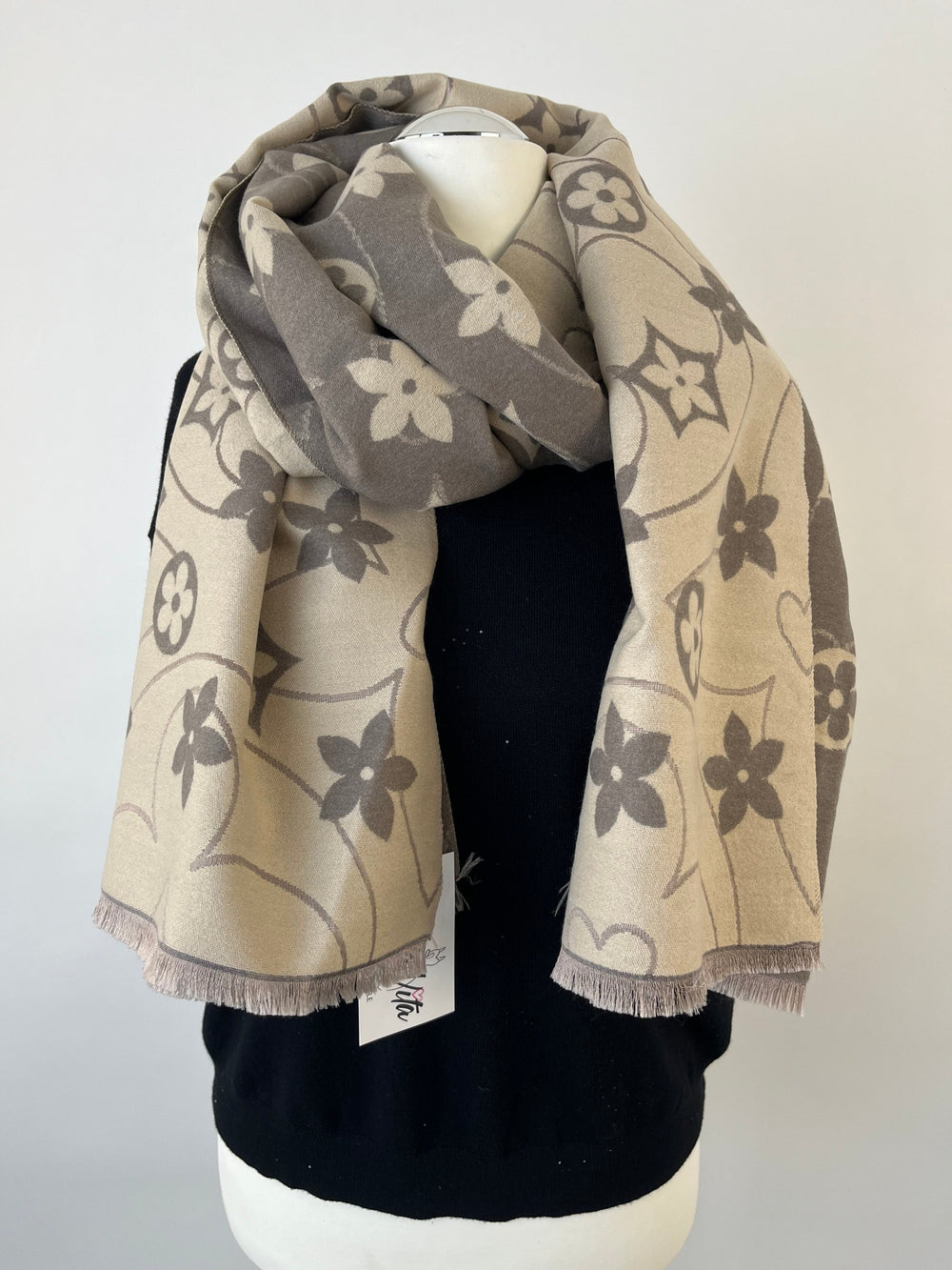 Beigegrauer Wendeschal mit Blumenmuster und Fransen am schwarzen Mannequin