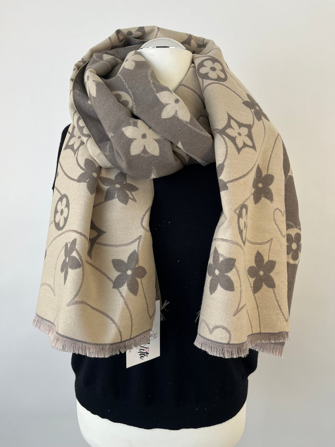 Beigegrauer Wendeschal mit Blumenmuster und Fransen am schwarzen Mannequin