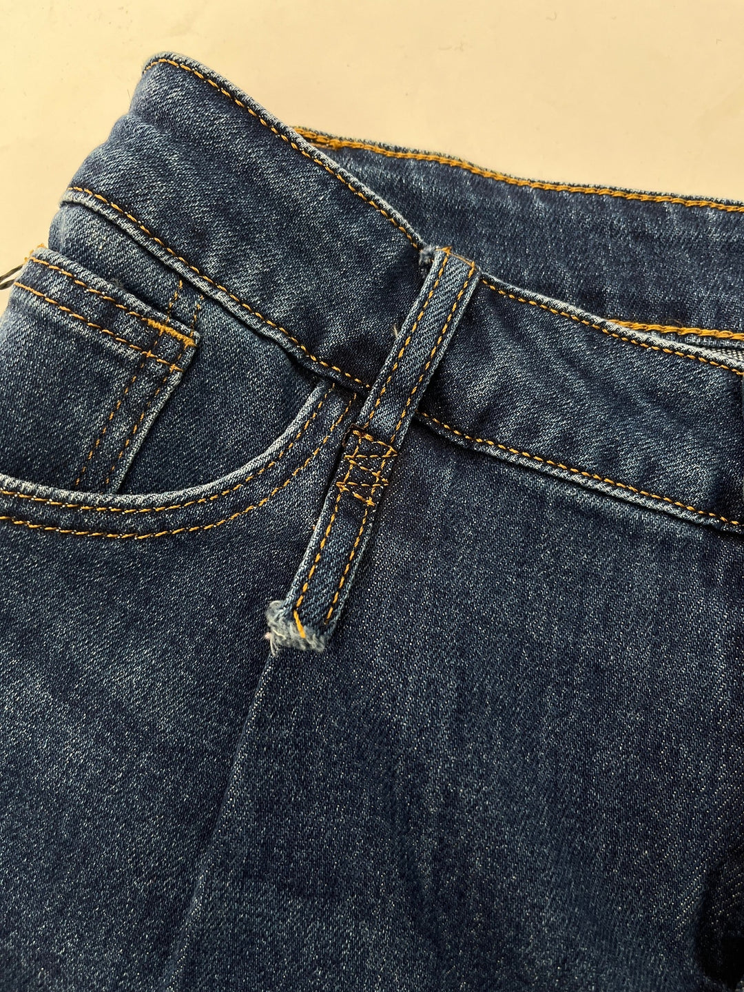 Nahaufnahme dunkelblaue Wide Leg Jeans mit gelber Kontraststeppung an der Tasche